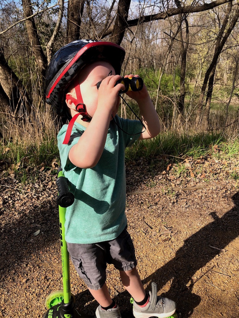 child on scooter looking through binoculars