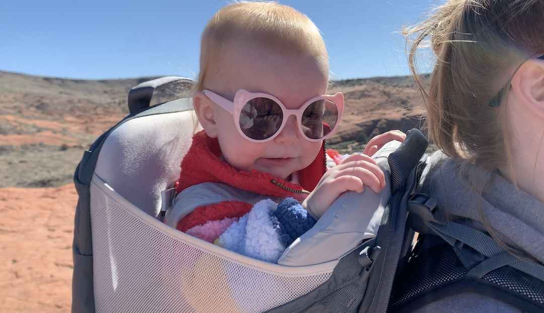 baby in backpack wearing sunglasses on family vacat