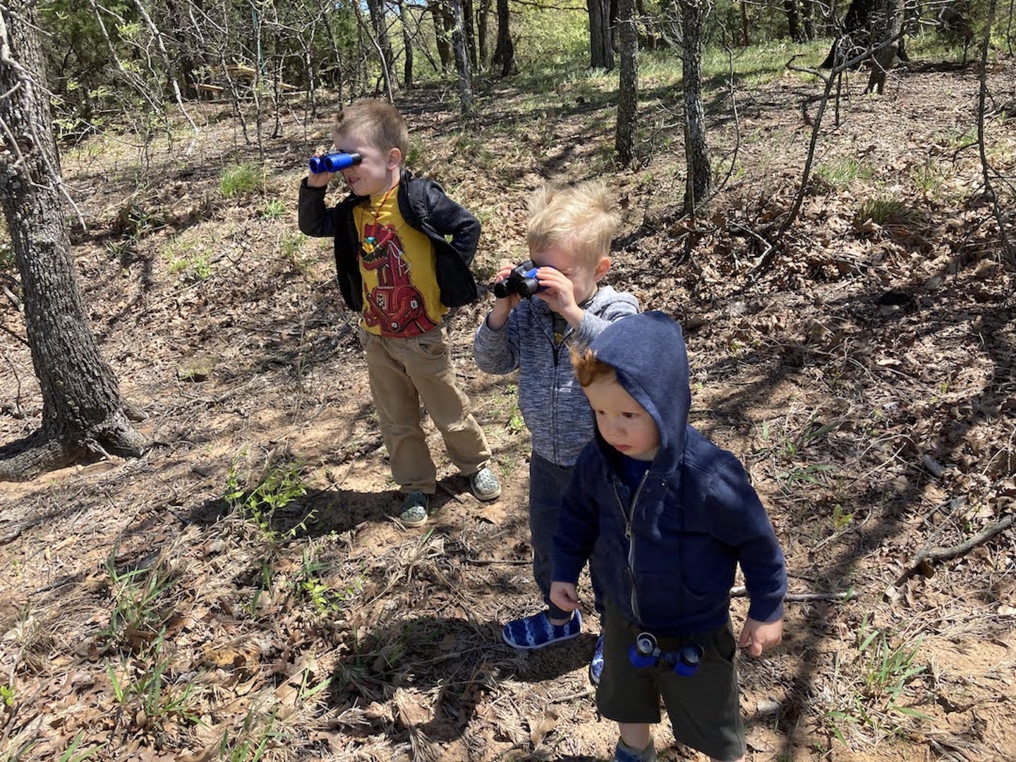 3 young boys looking through binoculars