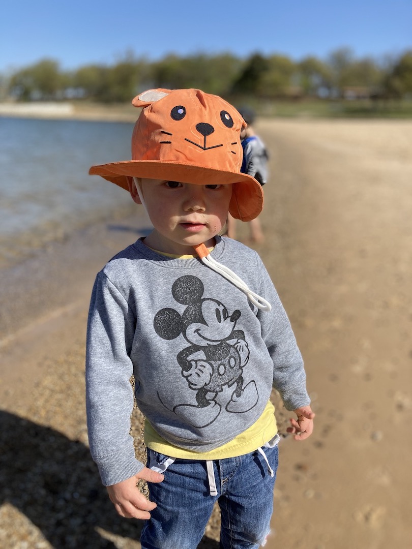 little boy wearing orange fox hat on beach