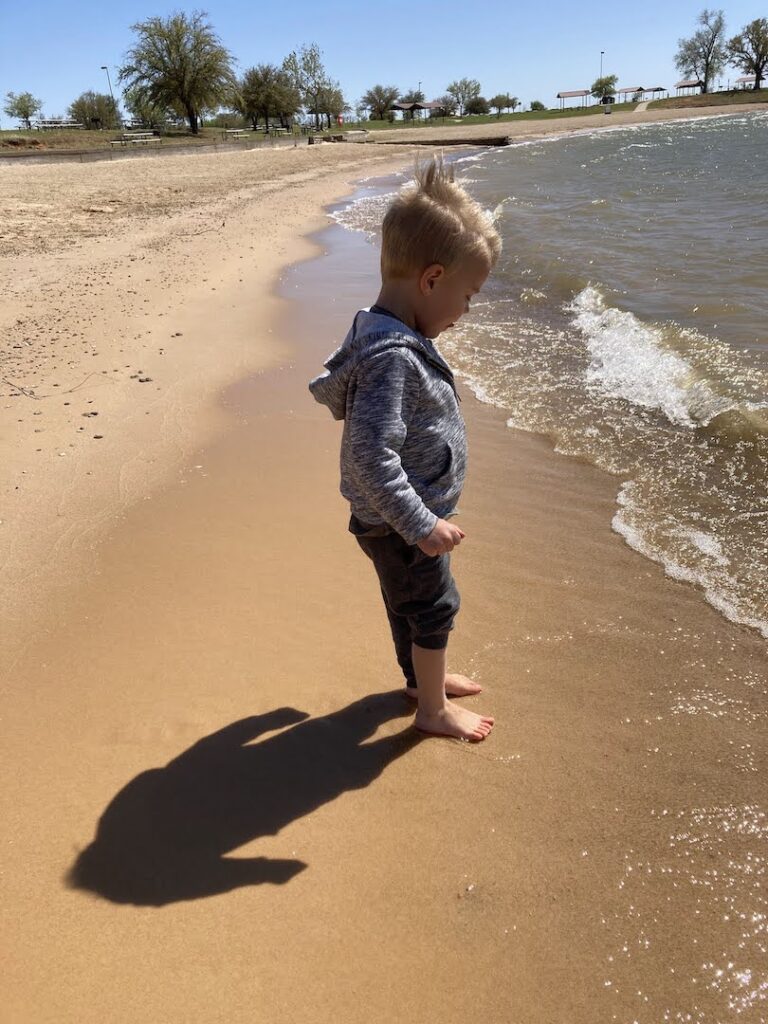 child barefoot in the sand while camping