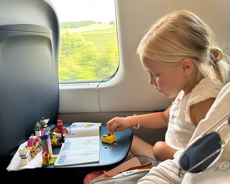 little girl playing with classic Legos on train