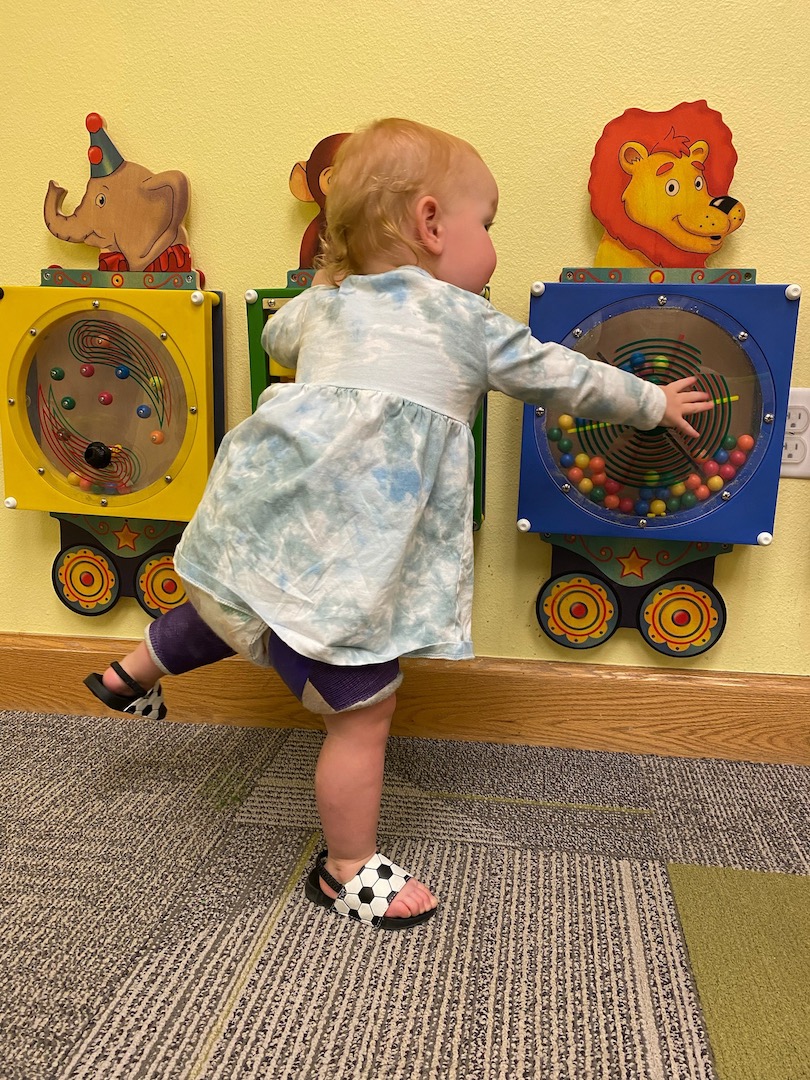 child in spica cast playing with wall toys at the doctor's office 